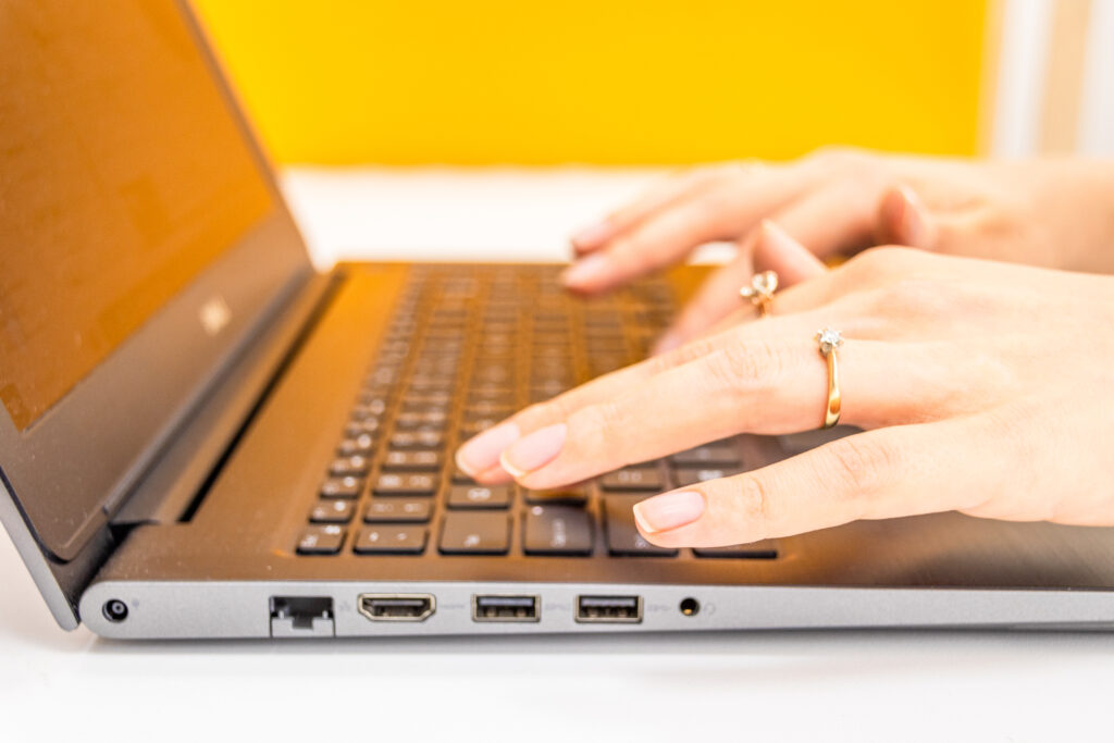 Zbliżenie na klawiaturę laptopa, damskie dłonie na klawiaturze