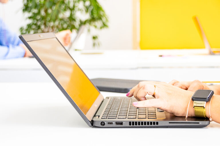 Otwarty laptop, kobiece dłonie piszące na klawiaturze